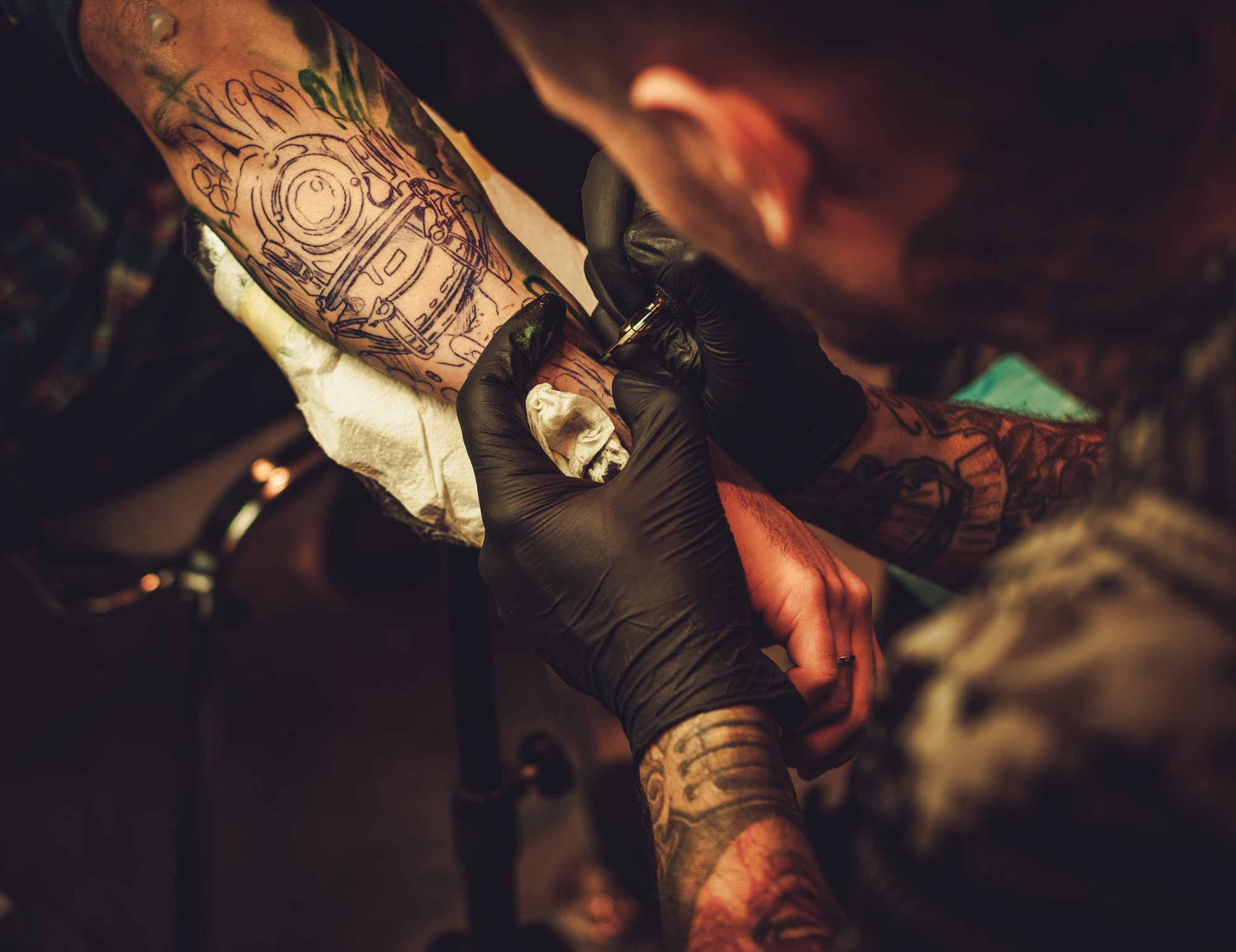Tattoo artist makes a tattoo on a man's hand.