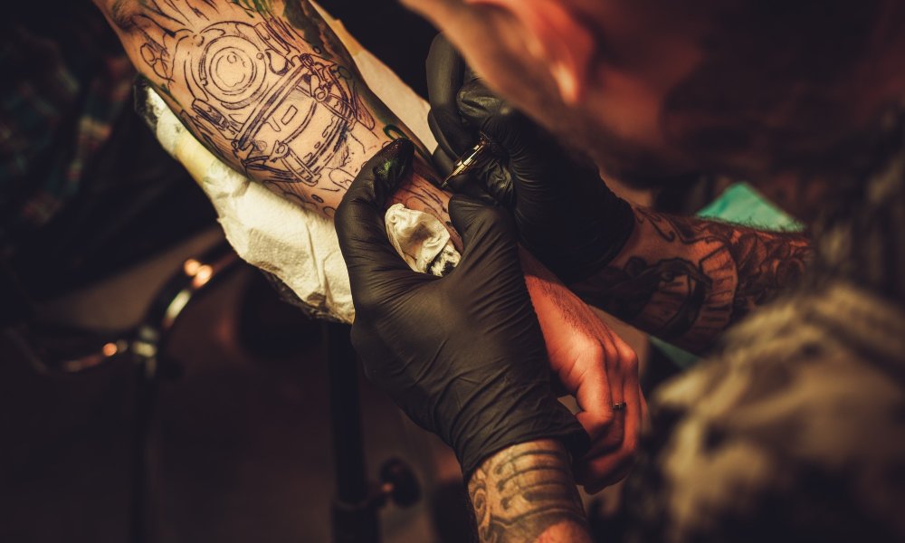 Tattoo artist makes a tattoo on a man's hand.