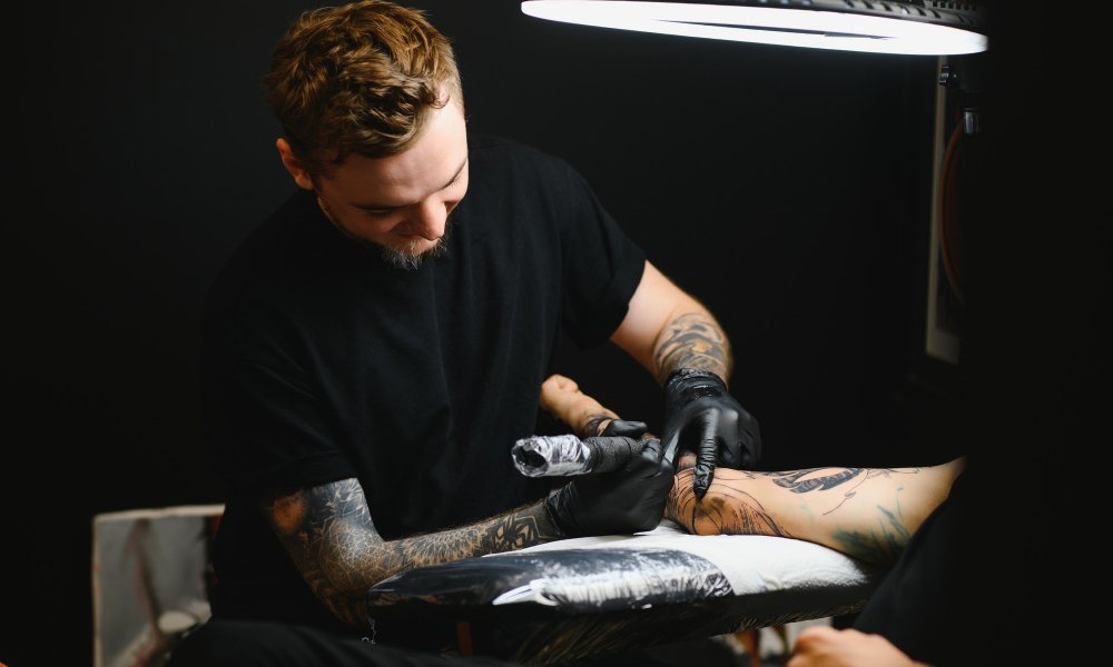 tattooist with his machine tattooing on the arm with the design drawn, concept of art and design